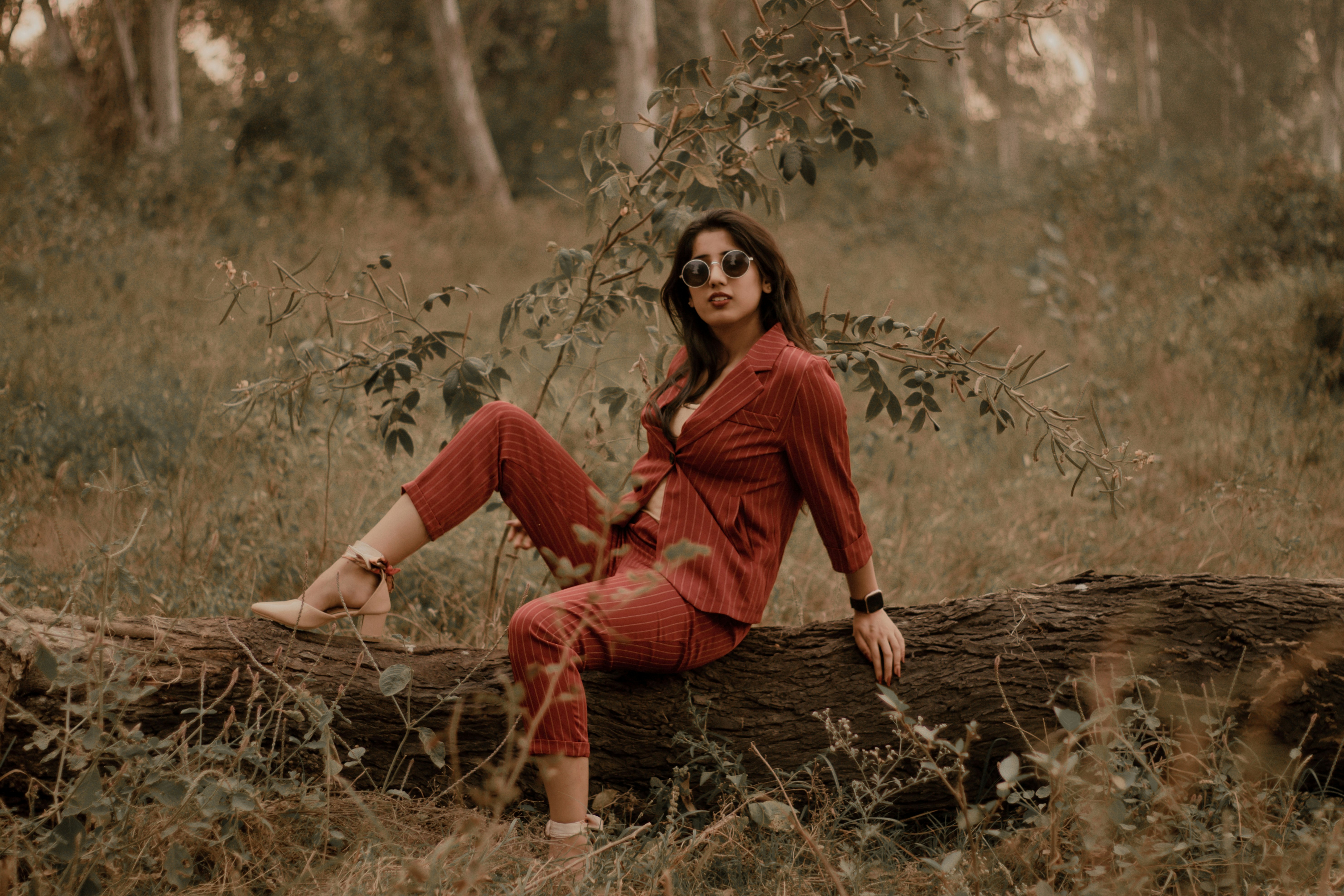 woman in red long sleeve shirt sitting on brown dried leaves